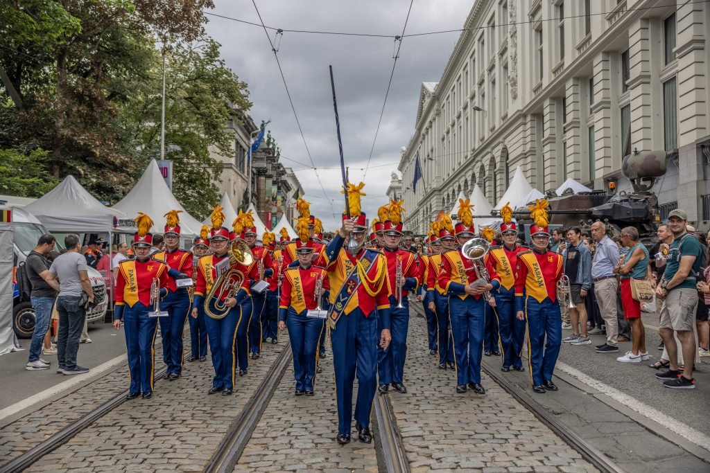 Fanfare en uniformes rouges et jaunes défilant dans une rue de Bruxelles