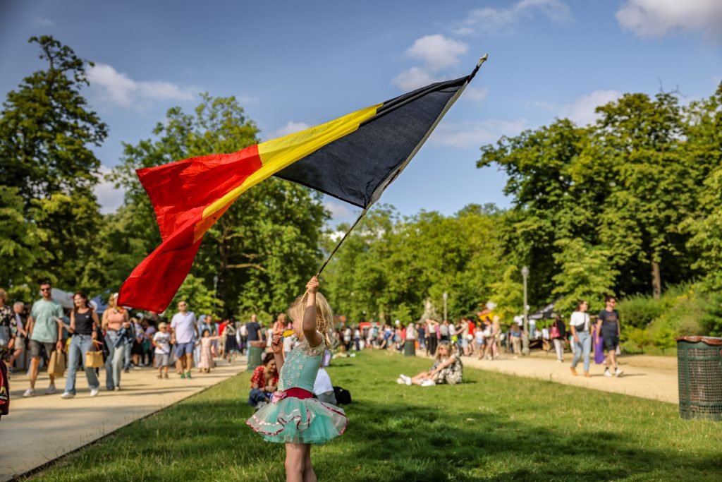 Enfant agitant un grand drapeau belge sur la pelouse du parc
